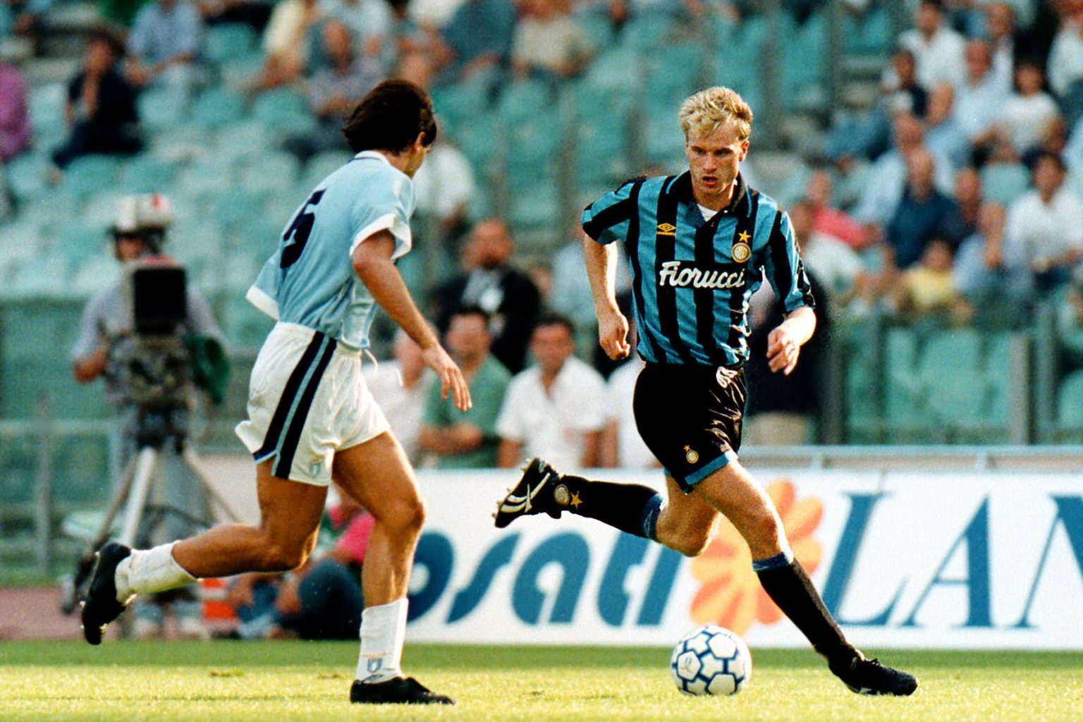  Dennis Bergkamp is playing for Inter Milan, he is running with the ball past an AS Roma player.